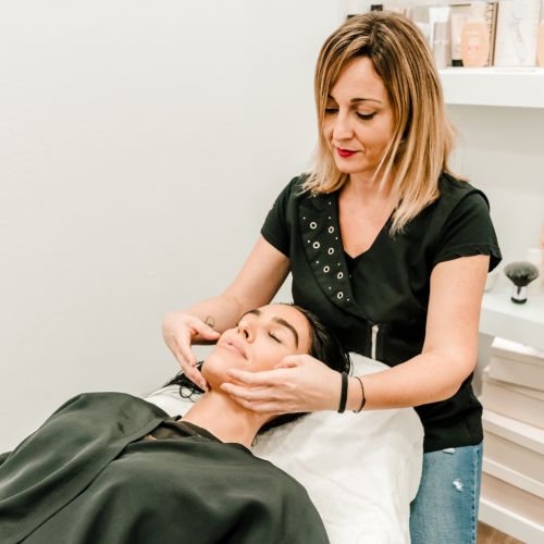 Tratamiento de belleza en nuestro centro Atrevit en Ciutadella. vemos a la clienta tumbada en camilla mientras una de nuestras esteticien realiza un masaje facial sobre la clienta. 
