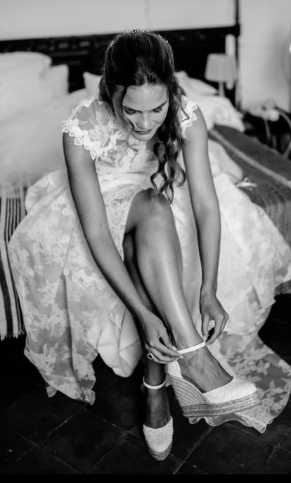 Fotografía de diseño en blanco y negro de novia preparando su calzado para asistir a su boda. 