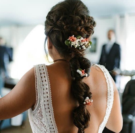 Imagen de novia preparada para la boda donde podemos ver un cabello largo trenzado y con decoración floral. 